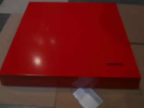 Rote, matte Frontverkleidung mit der Marke Remeha. Das Produkt ist flach und rechteckig, auf einem hellen Untergrund platziert.